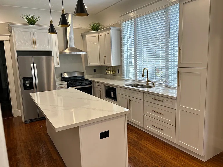 Renovated kitchen with white cabinets and quartz counters